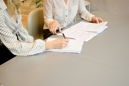 Personas sentadas en una oficina firmando contratos